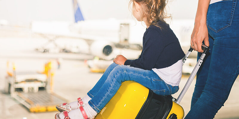 little girl on yellow suitcase