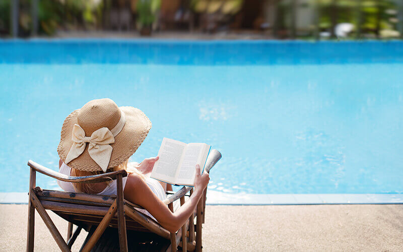 woman reading by swimming pool